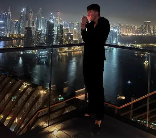 Leon on a balcony overlooking the Dubai skyline at night